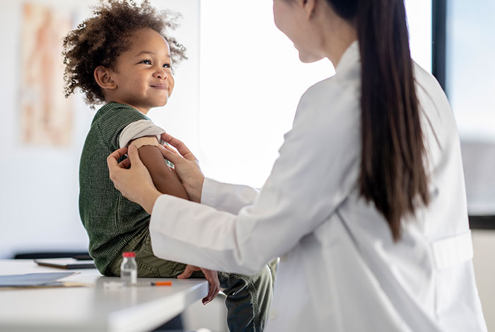 pediatrician applying bandage on young child after vaccination