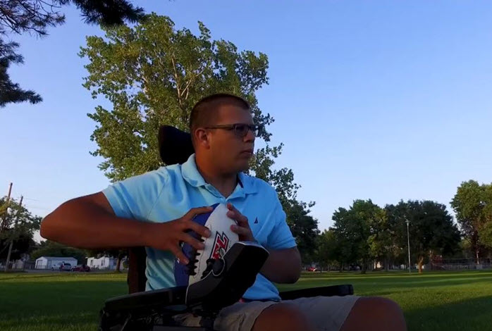 man in wheelchair holds football
