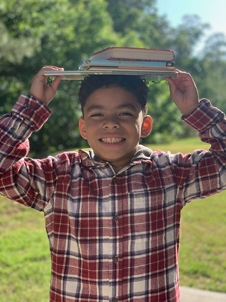 Child holding books on his head